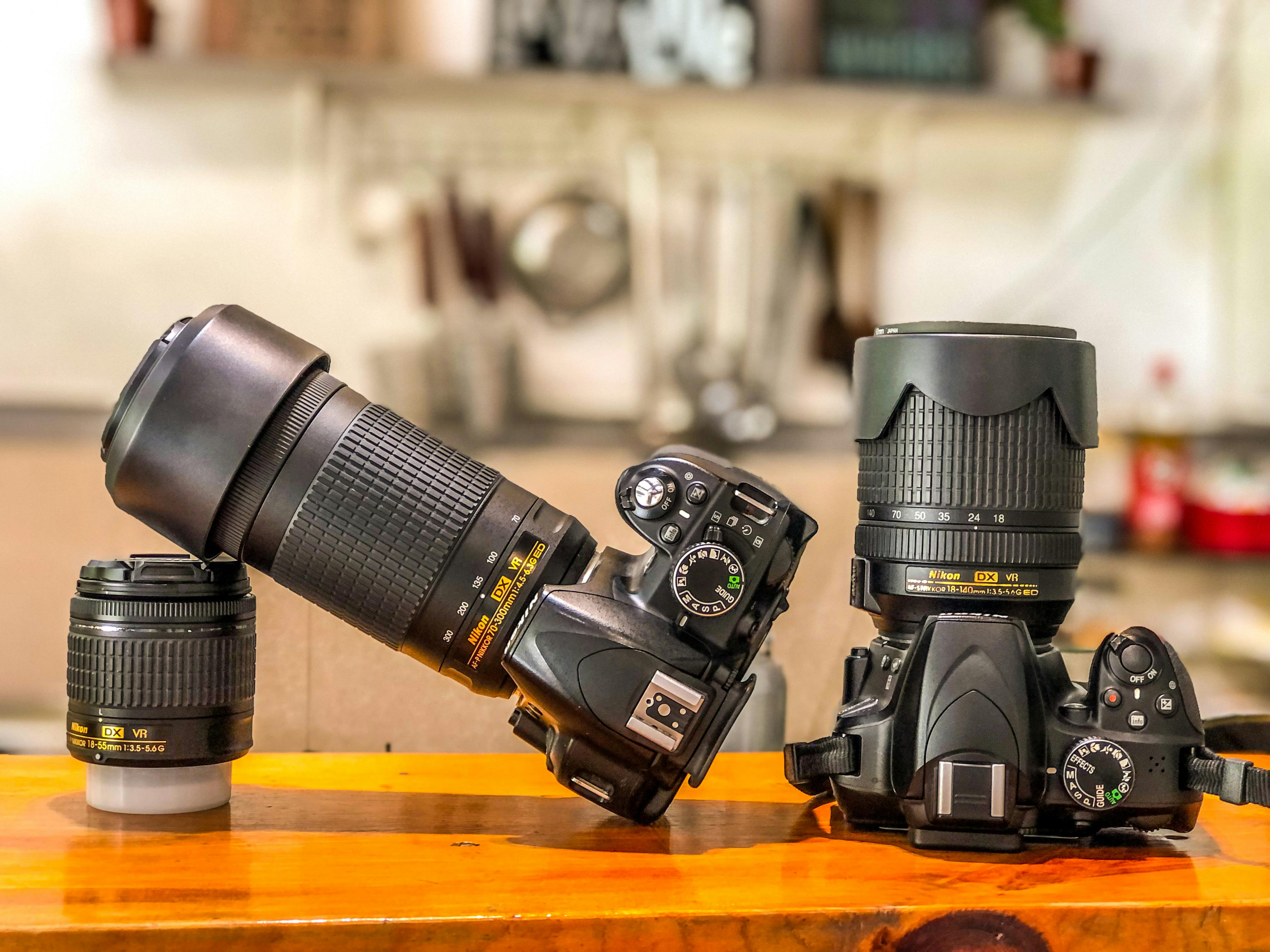Two DSLR type cameras on wooden table